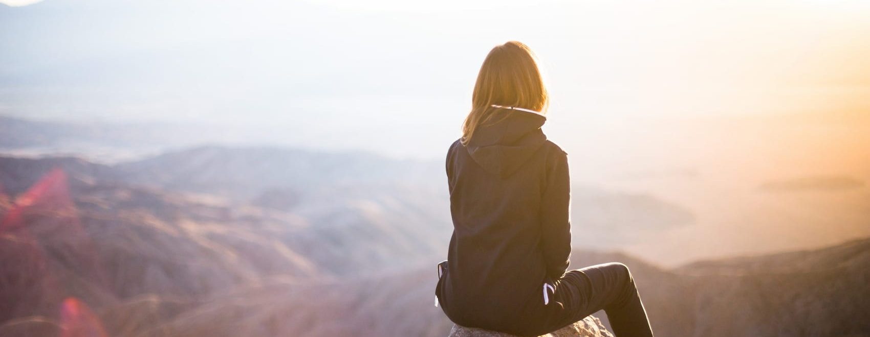 Photo of a woman on a mountain watching a spiritual sunrise