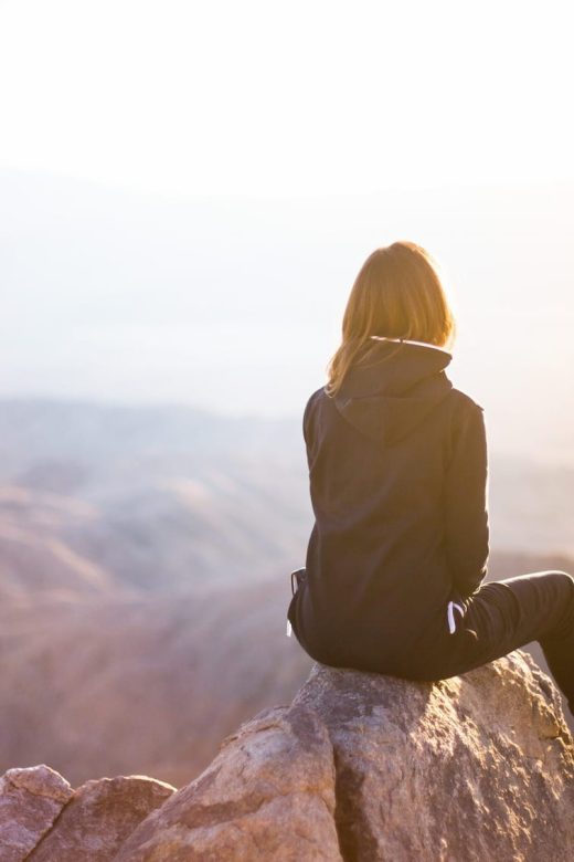 Photo of a woman on a mountain watching a spiritual sunrise